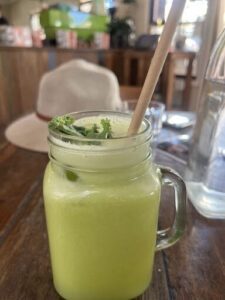A glass of green liquid with a straw in it.