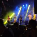 A group of musicians performing on stage in front of a crowd.
