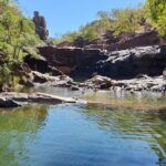 A group of people are enjoying a day at the river, swimming and playing in the water.