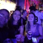 A group of people are standing together, enjoying drinks and having a good time.