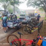 A group of people are working on bicycles, with a car nearby.