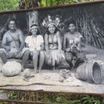 A group of people, including a man and a woman, pose for a picture in front of a sign.