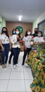 A group of people wearing face masks pose for a picture in front of a table with potted plants.