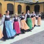 A group of women are dancing in a line, wearing long dresses and holding hands.
