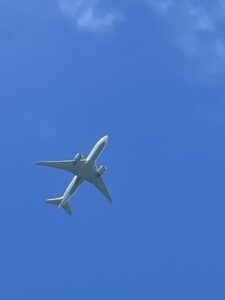 A large airplane flies through a clear blue sky.