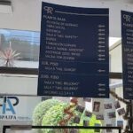 A large blue sign with white lettering is posted on a wall, providing information about the different types of food available.