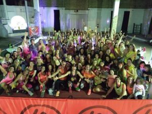 A large group of people are gathered together, some wearing pink, and others wearing yellow. They are all smiling and having a great time.
