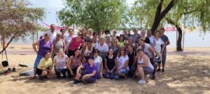A large group of women pose for a picture on the beach.