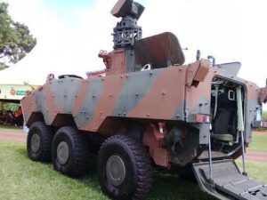 A large military vehicle is parked on a grassy field.