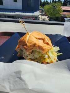 A large sandwich is served on a black plate, with lettuce and cheese.