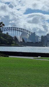 A large white building with a flag on top is situated next to a body of water.