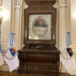 A large wooden display with a clock and a painting of a boat.