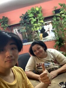 A man and a woman are sitting at a table, with the woman giving a thumbs up.