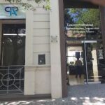 A man is standing in front of a building with a sign that says "Cia".