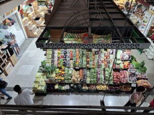 A man is standing in front of a fruit stand, looking at the variety of fruits available.