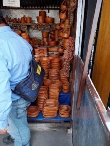 A man is standing in front of a shelf full of clay pots.