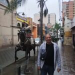 A man poses in front of a statue of a man on a horse.