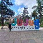 A man stands in front of a large sign that reads "Energia Viva."