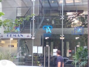 A man walks past a building with a large window, which has a logo for a company called "A".