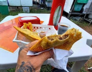 A person is holding a sandwich in their hand, with a tattoo visible on their arm.