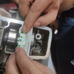 A person is working on a motorcycle, specifically focusing on the engine.