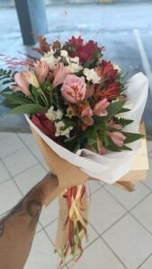 A person with a tattoo is holding a bouquet of flowers.