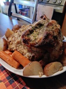 A plate of food with a roast chicken and potatoes.