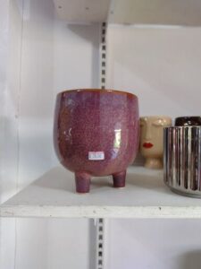 A purple vase with a price tag of $1.99 sits on a shelf.