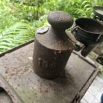A rusted metal container with a number 101 on it sits on a rusted metal surface.