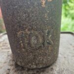A rusted metal container with the word "100" written on it.