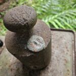 A rusty metal object with a coin on top of it.
