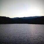 A serene lake at sunset with mountains in the background.