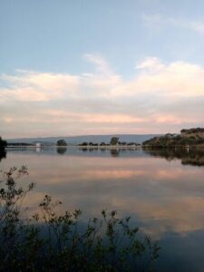 A serene scene of a lake with a few boats and a beautiful sunset in the background.