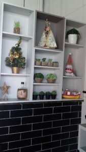 A shelf with a variety of potted plants and a bottle of liquor.