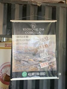 A sign advertising a restaurant hangs from a pole.