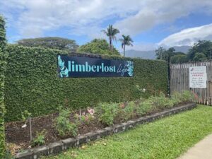 A sign for a lodge is surrounded by green bushes.