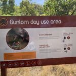 A sign is posted on a wooden pole, providing information about the Gunlom Day Use Area.