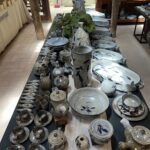 A table full of various dishes and cups, including a blue and white vase.