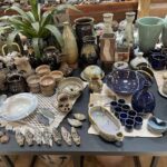 A table full of various pottery items, including vases, bowls, and cups.