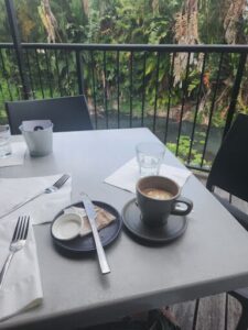 A table with a cup of coffee, a plate of food, and a knife.