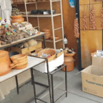 A table with a variety of pottery, including vases and bowls, is displayed in a room.