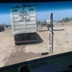 A truck with a cross on the side is driving down a dirt road.