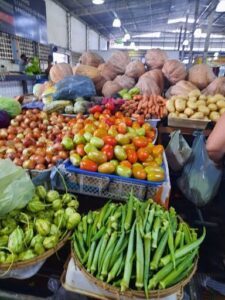 A variety of fresh vegetables are displayed at a market, including tomatoes, potatoes, and squash.