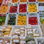 A variety of spices and seasonings are displayed in a store, including peppers, onions, and garlic.