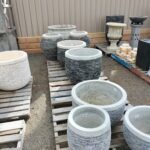 A variety of vases are displayed on a wooden table, with some of them being made of stone.