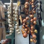 A variety of vegetables are hanging from the ceiling, including onions, garlic, and corn.