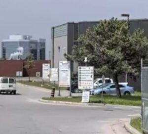 A white van is driving down a street past a building with a sign on it.