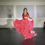 A woman in a red dress is dancing on a stage.