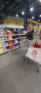 A woman shopping at a grocery store with a cart full of food.