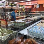 A woman shopping in a grocery store with a large selection of food items.